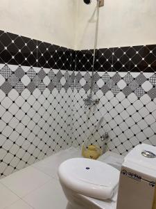 a bathroom with a white toilet and black and white tiles at Alpine Resort Khaplu in Khaplu