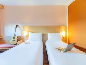 a room with two beds with a laptop and a guitar at Hotel Ibis Lisboa Sintra in Sintra