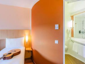 a hotel room with a guitar on a bed and a bathroom at Hotel Ibis Lisboa Sintra in Sintra