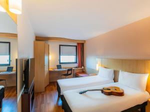 a hotel room with two beds and a desk at Hotel Ibis Lisboa Sintra in Sintra