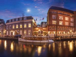 a boat in a river in front of buildings at Sofitel Legend The Grand Amsterdam in Amsterdam