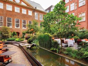 a garden with a pond in front of a building at Sofitel Legend The Grand Amsterdam in Amsterdam