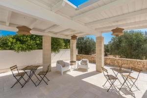 a patio with chairs and tables under a pavilion at Tenuta Pietraviva by Perle di Puglia in Maruggio +2 photos