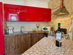 a kitchen with red cabinets and two wine glasses on a counter at La casetta di Ninni in Rocca Cinquemiglia