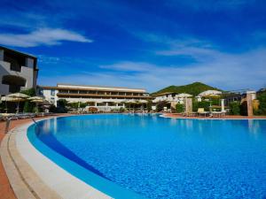 拉卡勒塔Cala della Torre的度假村内的大型游泳池,配有遮阳伞 更多78张照片