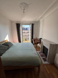 Schlafzimmer mit einem Bett, einem Kamin und einem Fenster in der Unterkunft Haussmannian Appartment, Charm & Unobstructed view in Paris