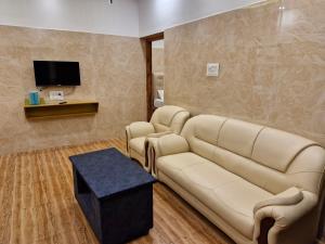 a waiting room with a couch and a tv at Saraa Grand in Kuttālam