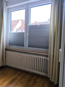 two windows with blinds and a radiator in a room at Nettes Schlafzimmer mit Gemeinschaftsbad in zentraler Lage in Bremen