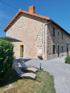 two lounge chairs in front of a stone house at La Petite Ferme Aux Prés in Saint-Germain-Lespinasse