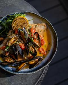 a bowl of food with seafood and mussels on a table at Harbour Hotel & Spa Christchurch in Christchurch