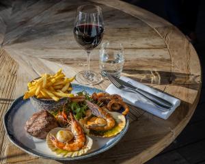 a table with a plate of food and a glass of wine at Harbour Hotel & Spa Christchurch in Christchurch