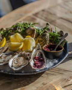 a plate of oysters and vegetables on a wooden table at Harbour Hotel & Spa Christchurch in Christchurch