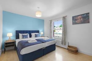 ein blaues Schlafzimmer mit einem großen Bett und einem Fenster in der Unterkunft The Charming 3 Bedroom House at Blakes Cottages in Reading