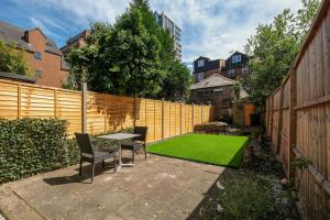 einen Garten mit einem Tisch und einer grünen Wiese in der Unterkunft The Charming 3 Bedroom House at Blakes Cottages in Reading
