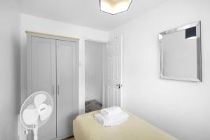 ein weißes Zimmer mit einem Bett und einem Ventilator in der Unterkunft The Charming 3 Bedroom House at Blakes Cottages in Reading + 28 Fotos