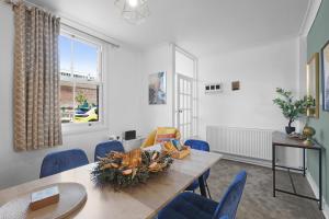 ein Esszimmer mit einem Tisch und blauen Stühlen in der Unterkunft The Charming 3 Bedroom House at Blakes Cottages in Reading