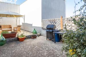 Un patio con parrilla y algunas plantas y una sombrilla. en Dimora Enea con idromassaggio -Salento Reservation, en Ugento 30 fotos más