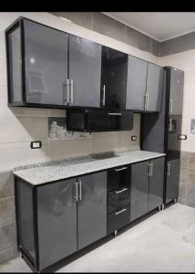 a kitchen with black cabinets and a counter top at Nile Pearl Apartment in Mît Khamîs