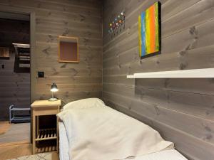 a bedroom with a bed and a wooden wall at Riddertunets toppleilighet in Beitostøl