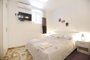 une chambre blanche avec un lit avec des serviettes dessus dans l'établissement Studio Apartment Laura, à Zadar