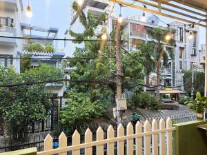 a white picket fence with a tree in a city at Four P Home - Binh Thanh in Ho Chi Minh City