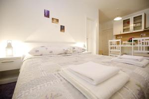 une chambre blanche avec un lit avec des serviettes dessus dans l'établissement Studio Apartment Laura, à Zadar
