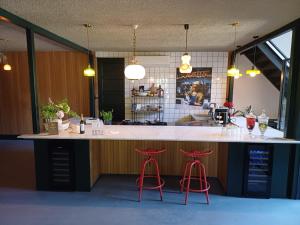 a kitchen with a large counter with two red bar stools at B&B Boudevino in Lekkerkerk