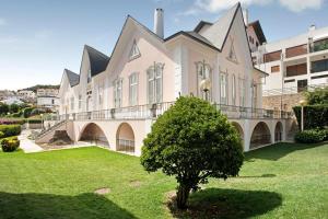 a large white building with a tree in the yard at Apartamento Vista Baia in São Martinho do Porto