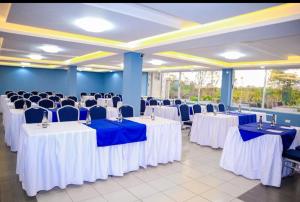 a banquet hall with white tables and blue chairs at Miugu Village Hotel in Murangʼa