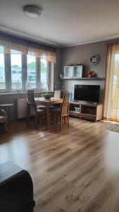 un soggiorno con tavolo, sedie e televisione di CHILLIapartamenty - FREDRY a Kołobrzeg