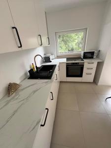 a white kitchen with a sink and a window at Gemini Lux - Sun Balaton in Balatonkenese
