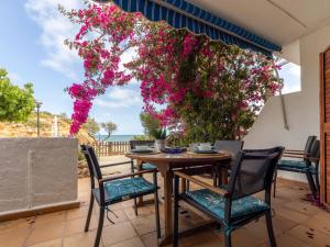 a table and chairs on a patio with pink flowers at POSIDONIA - Espectaculares vistas al mar in L'Ampolla