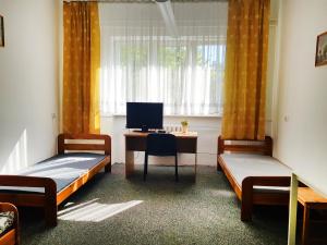 a room with two beds and a desk with a computer at mHostel24 in Lublin