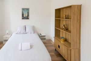 a bedroom with a white bed and a wooden cabinet at Studio - Washington 4 in Le Havre