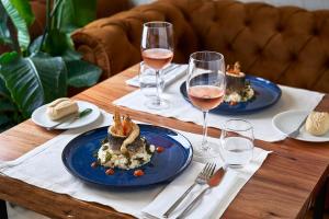 a wooden table with two plates of food and wine glasses at The Log Porto Hotel by Piamonte Hotels in Porto