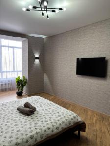 a bedroom with a bed and a flat screen tv at VIP кв 10 мкр in Oral