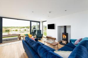 ein Wohnzimmer mit einer blauen Couch und einem Kamin in der Unterkunft Songbird SV30 Silverlake Dorset in Warmwell