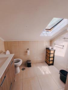 a bathroom with a toilet and a skylight at Lisbon Soul Surf Camp in Cascais +54 photos