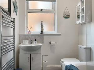 Un baño con lavabo, inodoro y ventana. en 2BR Filey Flat, Near Seafront - Perfect for Getaways, en Filey