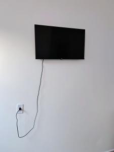 Un televisor de pantalla plana colgado en una pared blanca en Suíte Da Rosa, en Cachoeira Paulista