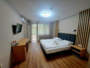 a bedroom with a bed and a desk and a television at Хотел Ресторант Ваката in Teteven