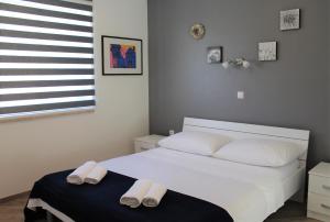 a bedroom with a white bed with slippers on it at Apartmani Marin in Vrbnik