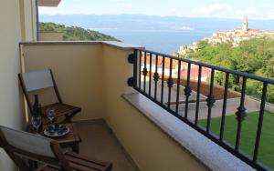 a balcony with a table and a chair and the ocean at Apartmani Marin in Vrbnik