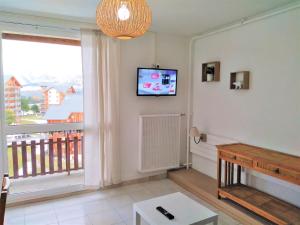 a living room with a television and a balcony at Le Cocon Alpin in Le Dévoluy