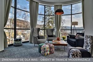 a living room with a couch and chairs and windows at Hotel Krynica Conference & SPA in Krynica Zdrój