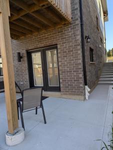 a chair sitting on a porch next to a brick building at Spacious Luxury walk out Basement in Kitchener