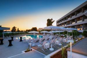 a hotel with a pool and chairs and umbrellas at Pharos Hvar Bayhill Hotel in Hvar