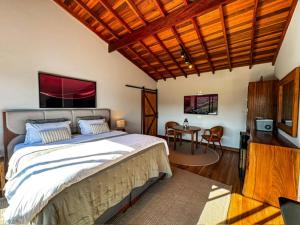 a bedroom with a large bed and a table at Chalé - Vila Bertina in Gonçalves