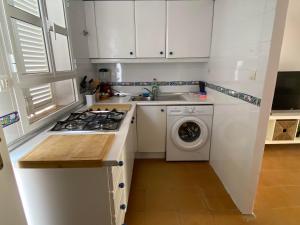 a white kitchen with a sink and a washing machine at BRISA del MAR in Isla Cristina +6 photos