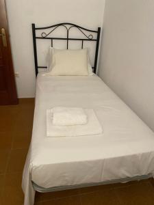 a bed with a black frame and a white towel on it at BRISA del MAR in Isla Cristina